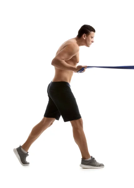 Sporty young man training with resistance band against white background — Stock Photo, Image