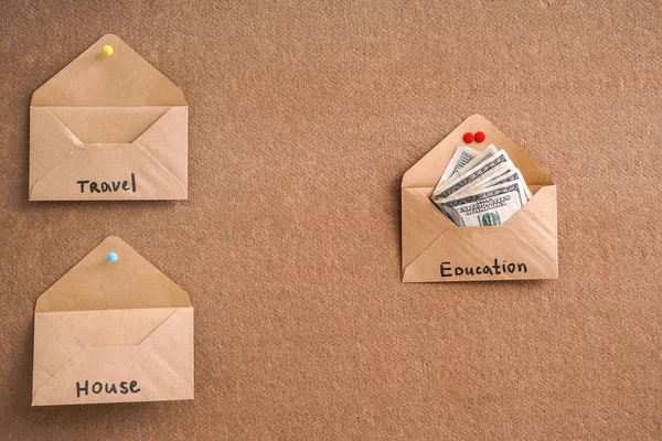 Envelopes with money for different needs on color background. Concept of savings