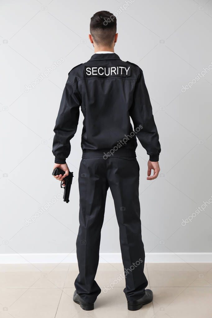 Male security guard near light wall
