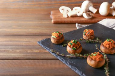 Ahşap masa üzerinde lezzetli mantar dolması ile kayrak plaka