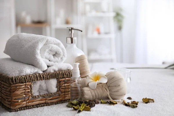 Handtücher, Kosmetika und Kräutertaschen auf dem Tisch im Wellnessbereich — Stockfoto