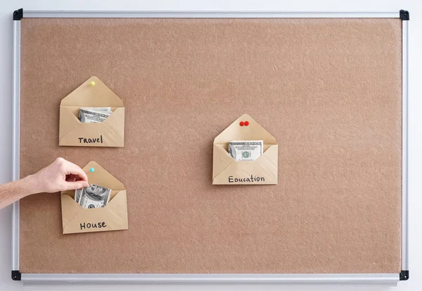 Envelopes with money for different needs on board. Concept of savings