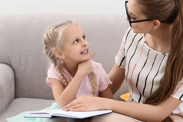 Little girl with speech therapist reading book in office — Stock Photo, Image