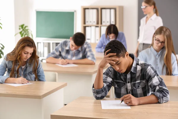 Alunos passando no teste escolar em sala de aula — Fotografia de Stock