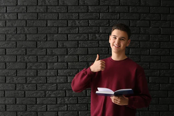 Karanlık arka planda Thumb-Up gösteren kitap ile Schoolboy — Stok fotoğraf