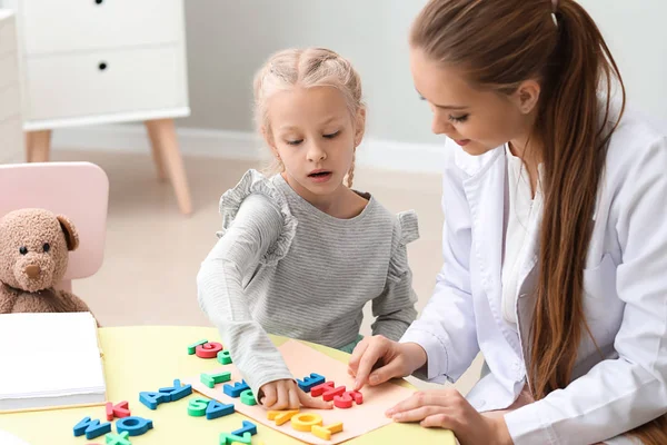 Kleines Mädchen mit Logopädin beim Verfassen von Buchstaben im Amt — Stockfoto