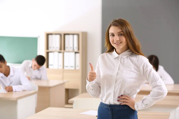 Onnellinen tyttö ohitettuaan koulun testi luokkahuoneessa — kuvapankkivalokuva