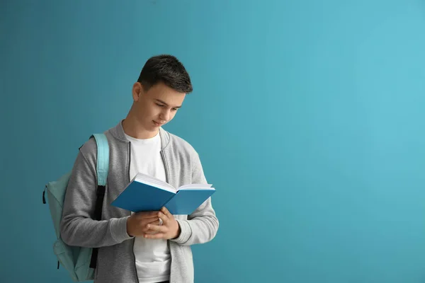 Schüler mit Buch auf farbigem Hintergrund — Stockfoto