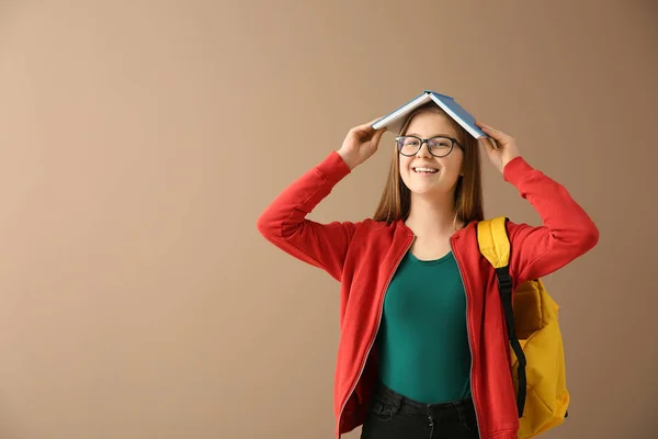 Schoolgirl with book on color background — Stock Photo, Image