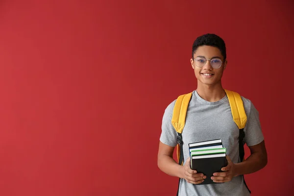 Estudante afro-americano com livros sobre fundo de cor — Fotografia de Stock