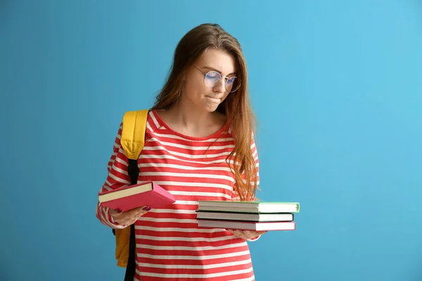 Colegiala con libros sobre fondo de color — Foto de Stock