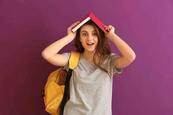 Schoolmeisje met boek op kleur achtergrond — Stockfoto