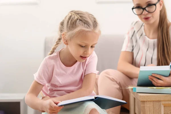 Mała dziewczynka czytania książki w biurze logopedy — Zdjęcie stockowe