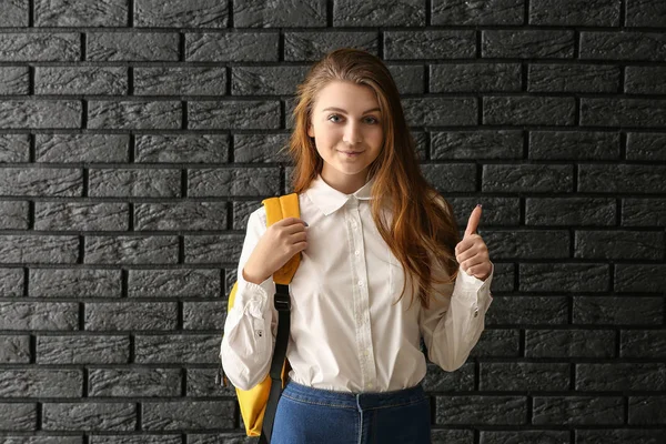Schoolgirl showing thumb-up on dark background — Stock Photo, Image