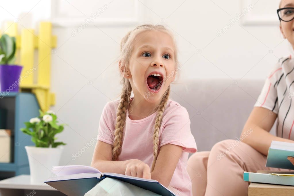 Little girl reading book at speech therapist office