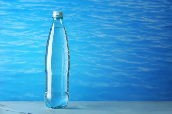 Butelka czystej wody na stole przed kolor tła — Zdjęcie stockowe