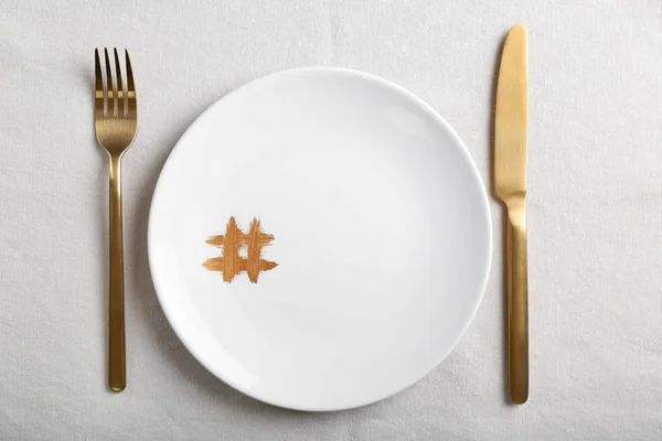 Plate with hashtag symbol and golden cutlery on light table — Stock Photo, Image