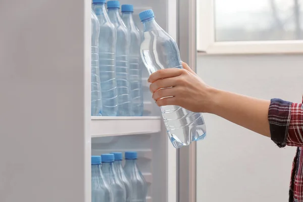 Женщина берет бутылку воды из холодильника в магазине — стоковое фото