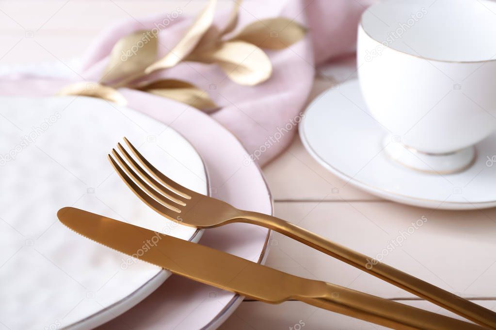Beautiful table setting with golden elements on wooden background, closeup