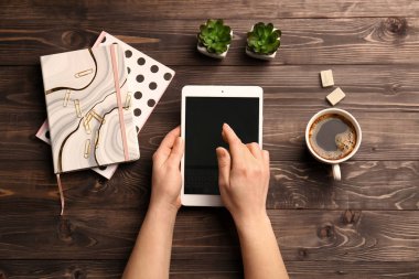 Tablet bilgisayar, fincan kahve ve defter ahşap arka plan üzerinde eller