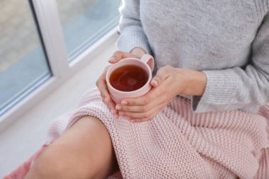 Genç kadın evde pencere sıcak çay içme