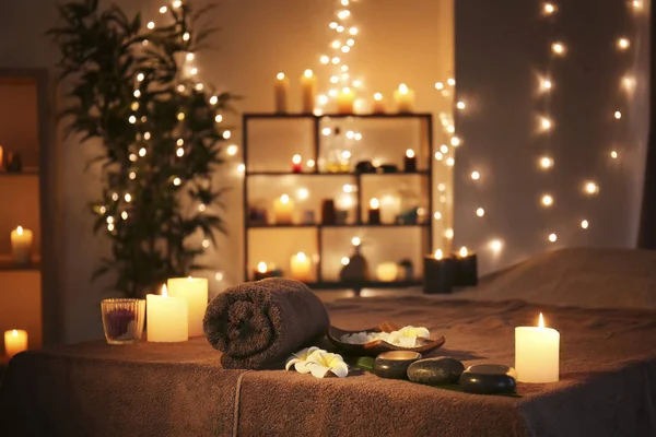 Massagesteine mit Handtuch und Kerzen auf dem Tisch im Wellnessbereich — Stockfoto