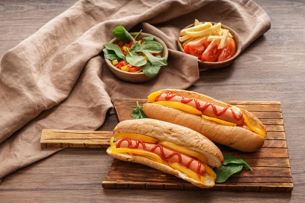 Deska z smaczne hot dogi na drewnianym stole — Zdjęcie stockowe