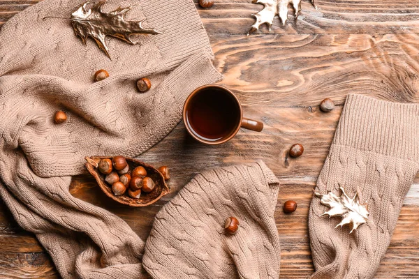 Composition with cup of hot tea, hazelnuts and golden leaves on wooden background — Stock Photo, Image