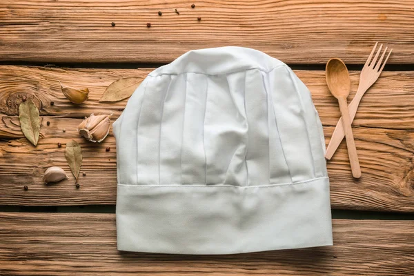 Composition with chef's hat on wooden table — Stock Photo, Image