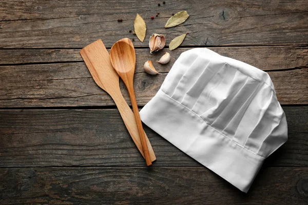 Chef's hat, spoon and shovel on wooden table — Stock Photo, Image