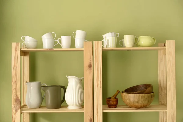 Conjunto de pratos limpos em prateleiras de madeira perto da parede de cor — Fotografia de Stock