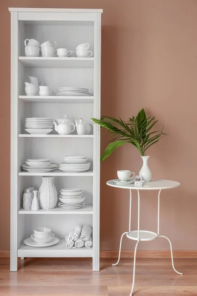 Conjunto de platos limpios en estantes cerca de la pared de color — Foto de Stock