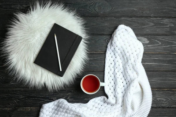 Composición con taza de té caliente, cuaderno y cuadros sobre fondo de madera —  Fotos de Stock