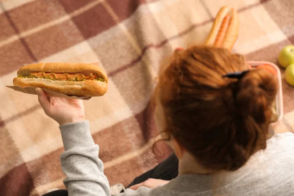 Mulher comendo cachorro-quente saboroso no piquenique — Fotografia de Stock