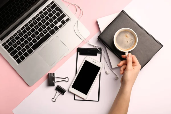 Main féminine avec tasse de café, ordinateur portable, ordinateur portable et téléphone portable sur fond clair — Photo