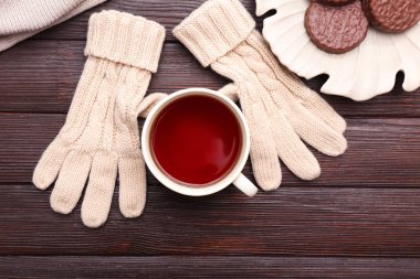 Fincan sıcak çay, sıcak eldiven ve ahşap zemin üzerine lezzetli Kurabiye