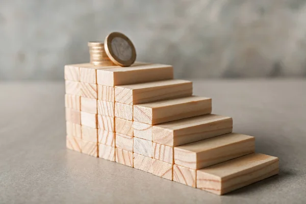 Stacked blocks with coins on grey table. Concept of career