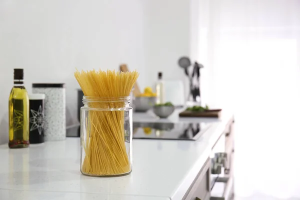 Droge pasta in een glazen pot op teller in keuken — Stockfoto