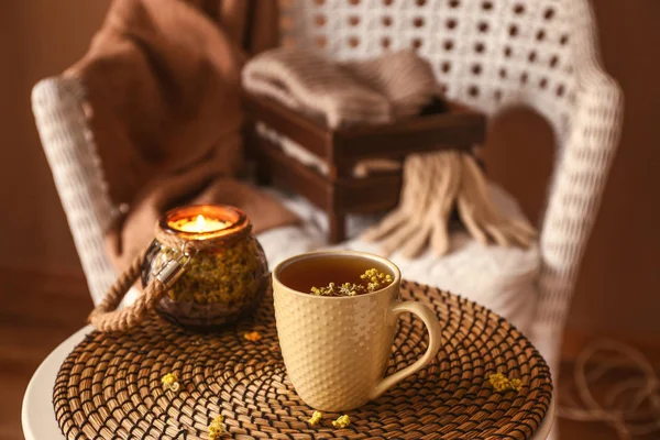 Cup of hot tea and holder with candle on wicker mat — Stock Photo, Image