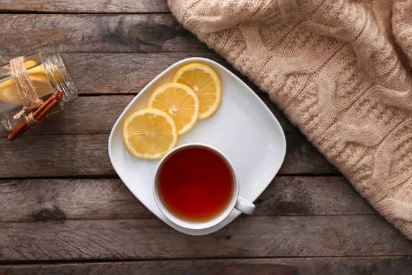 Plate with cup of hot tea and lemon on wooden table — Stock Photo, Image