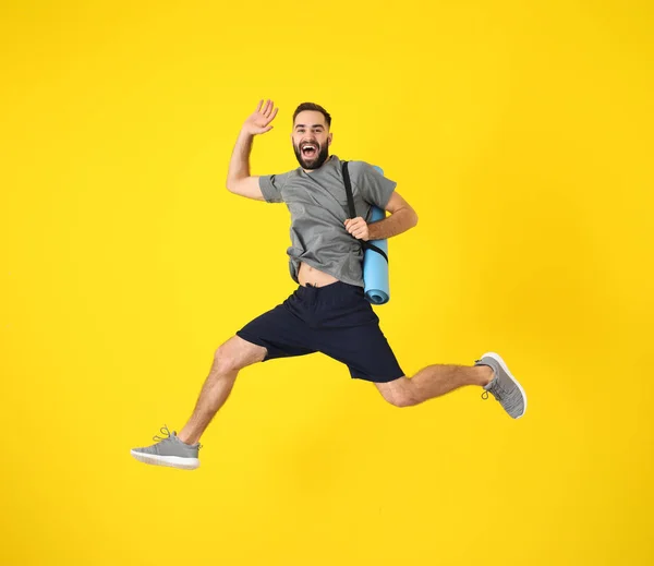 Young sporty man jumping against color background — Stock Photo, Image