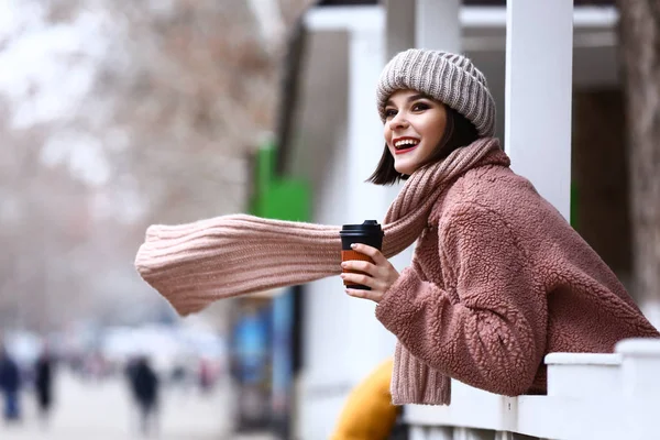 Retrato de mujer joven de moda en ropa de abrigo y con taza de café al aire libre —  Fotos de Stock