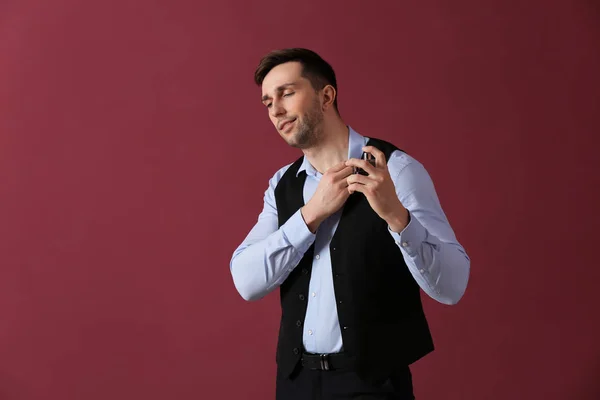 Handsome man with bottle of perfume on color background — Stock Photo, Image