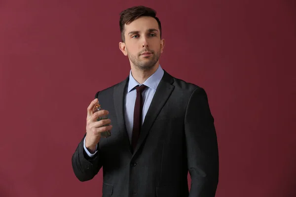 Handsome man with bottle of perfume on color background — Stock Photo, Image