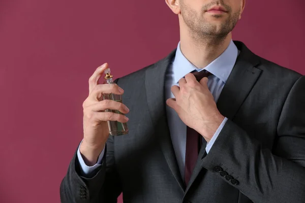 Hombre guapo con botella de perfume sobre fondo de color, primer plano — Foto de Stock