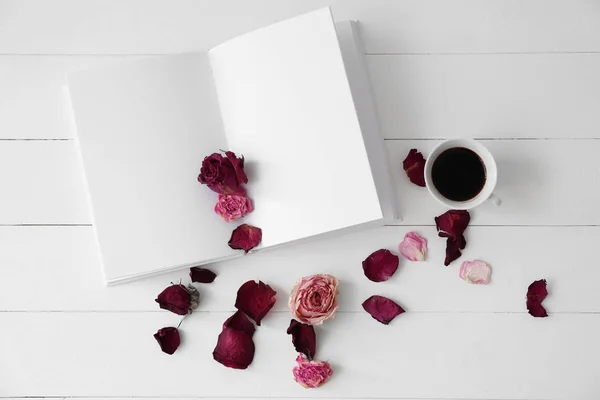 Livro, flores secas e xícara de bebida quente na mesa branca — Fotografia de Stock
