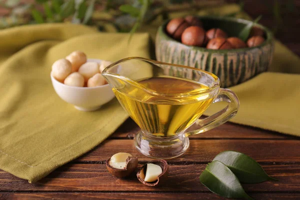 Oil with macadamia nuts on wooden table — Stock Photo, Image
