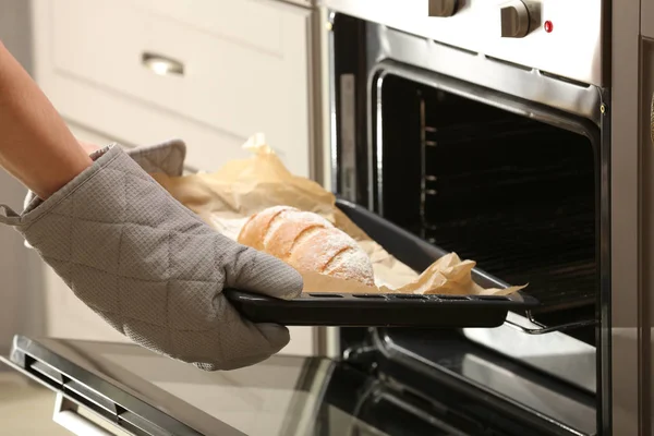 Taking of baking tray with homemade bread out of oven — Stock Photo, Image