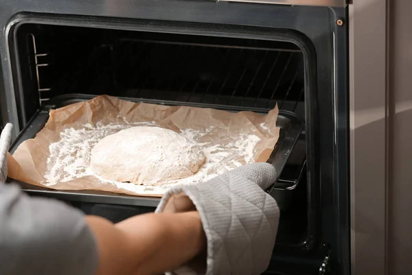 Colocação de assadeira com massa crua para pão em forno na cozinha — Fotografia de Stock