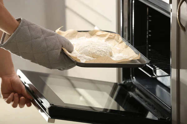 Colocação de assadeira com massa crua para pão em forno na cozinha — Fotografia de Stock